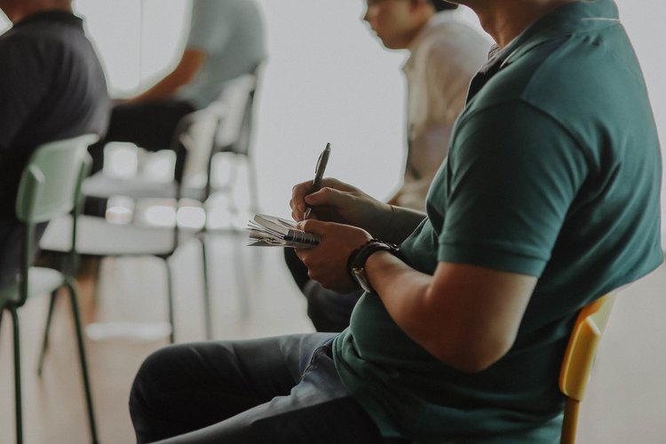 Person sitting in a chair taking notes on paper