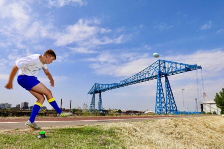 Matty Lynn kicking a ball over the Transporter Bridge | Tees Valley Combined Authority