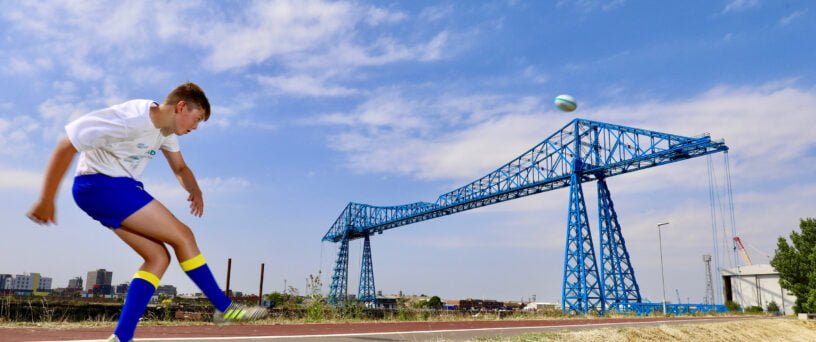 Matty Lynn kicking a ball over the Transporter Bridge | Tees Valley Combined Authority